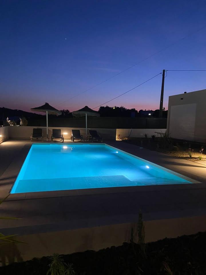 Vista noturna da piscina com iluminação envolvente e realce do espaço exterior